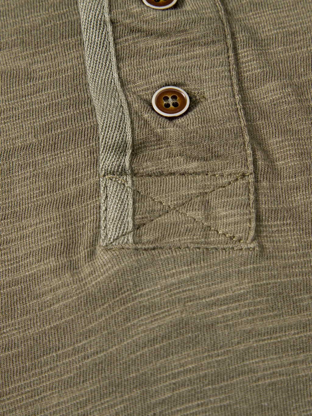 Henley-T-paidan nappilistan alaosan ompeluyksityiskohta