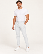 Valkoiset joustavat slim fit -housut aikuisen miesmallin yllä lämpimän valkoisessa studiossa